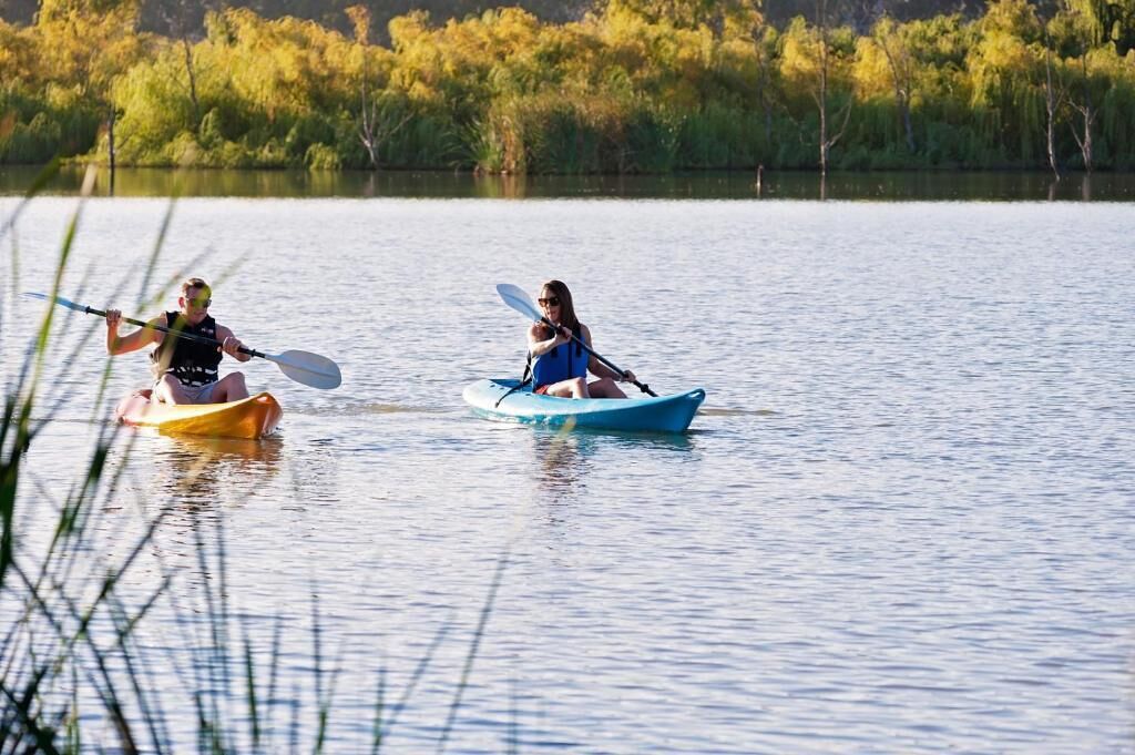 Due persone che fanno kayak su un lago calmo, circondato da alberi.