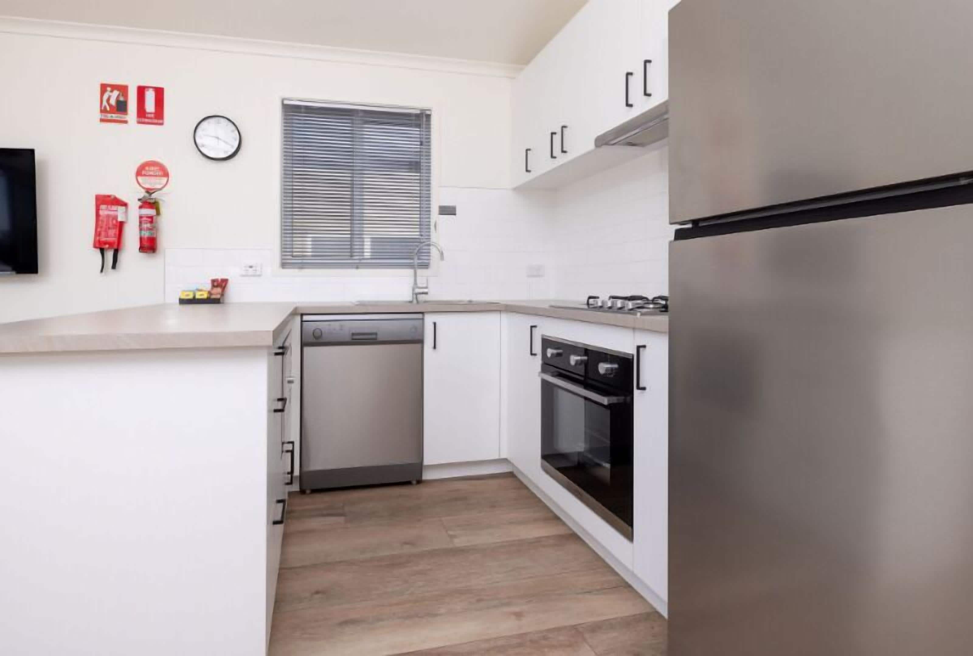Een moderne keuken met witte kasten, roestvrijstalen apparatuur en een houten vloer.