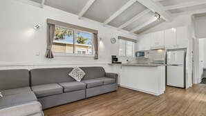 A modern kitchen with white cabinets, a grey sofa, and a wooden floor. - BIG4 Mannum Holiday Park (Mannum)