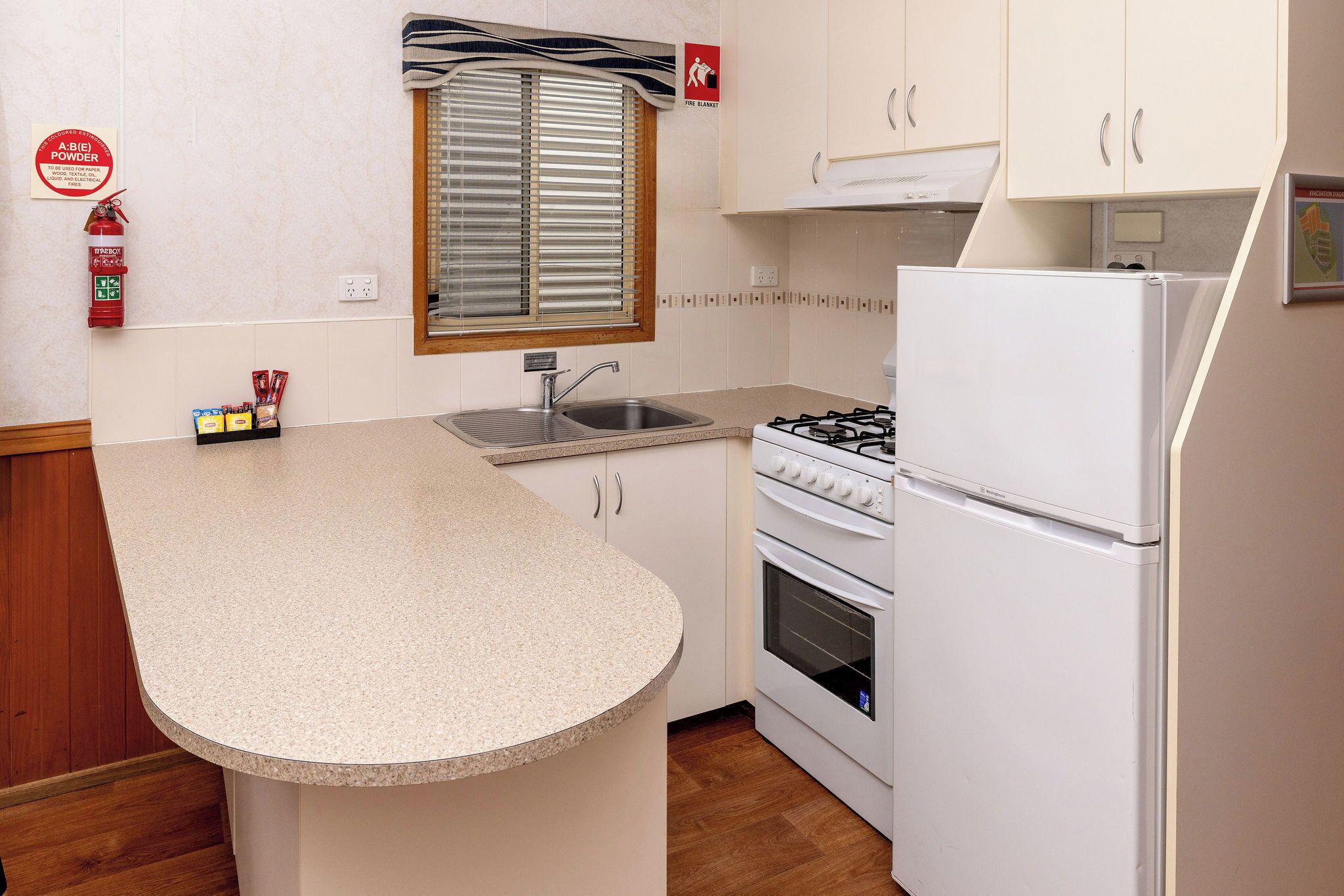 A compact kitchen with a built-in gas stove, a sink, and a white refrigerator.
