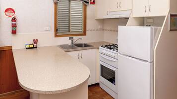 A compact kitchen with a built-in gas stove, a sink, and a white refrigerator.