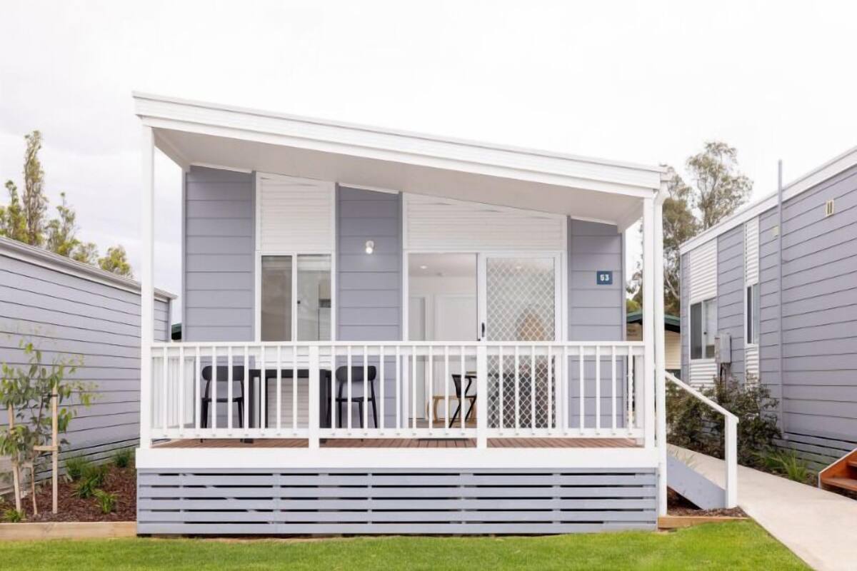 A modern single-story house with a covered porch, a small deck, and a staircase leading to the entrance.