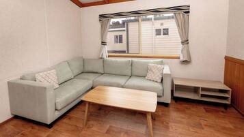 A living room with a sectional sofa, a wooden coffee table, and a window with curtains.