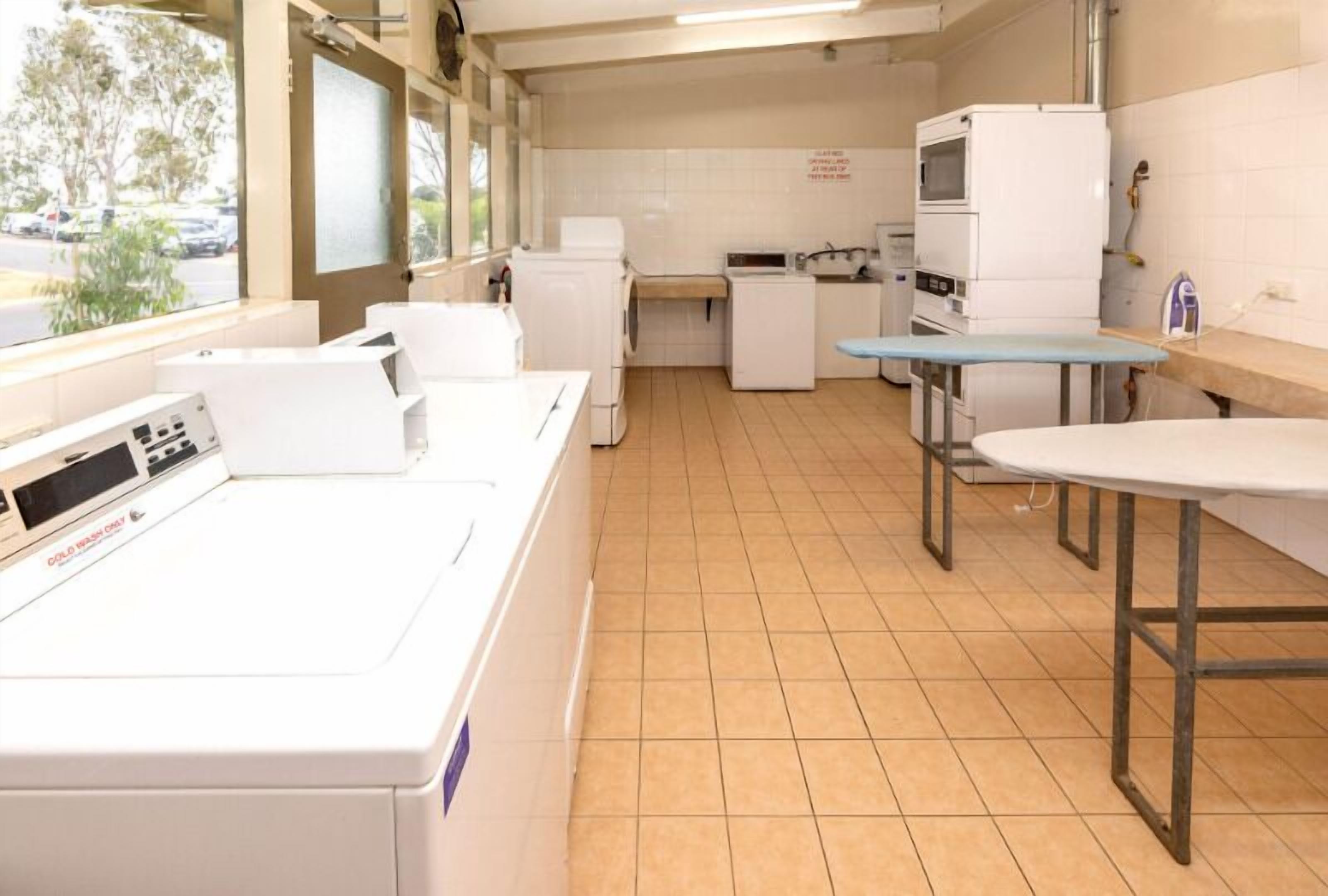 A laundry room with a washing machine, dryer, and ironing station.