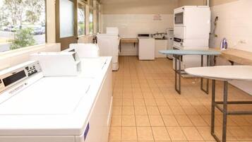 A laundry room with a washing machine, dryer, and ironing station.