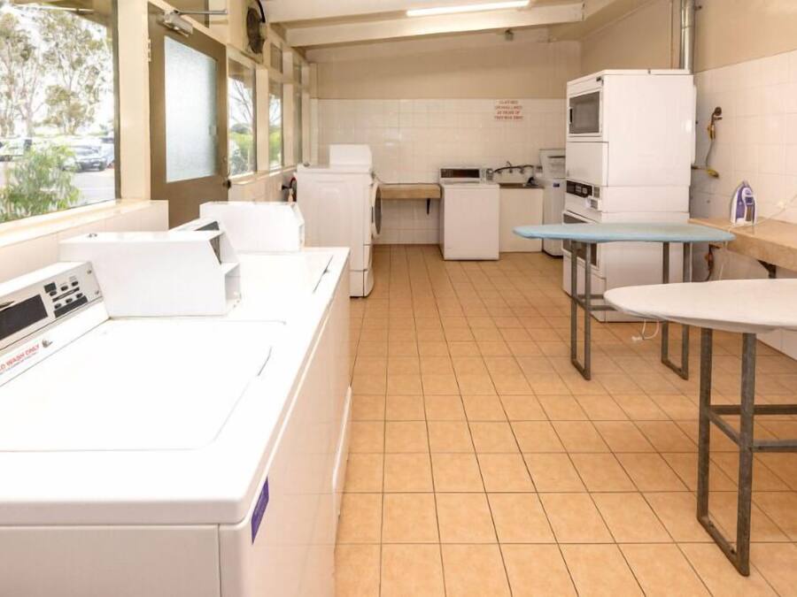 Un cuarto de lavandería con lavadora, secadora y plancha.