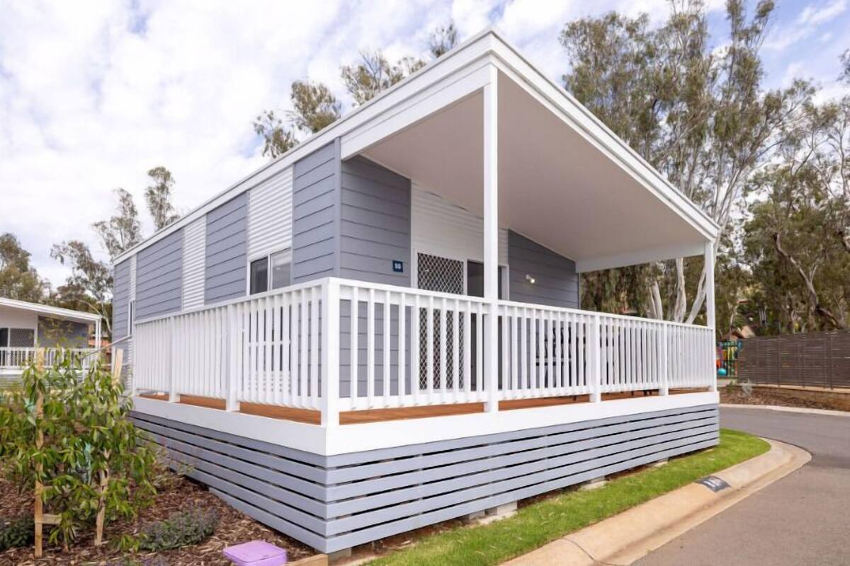 A single-story mobile home with a covered porch and a fenced yard.
