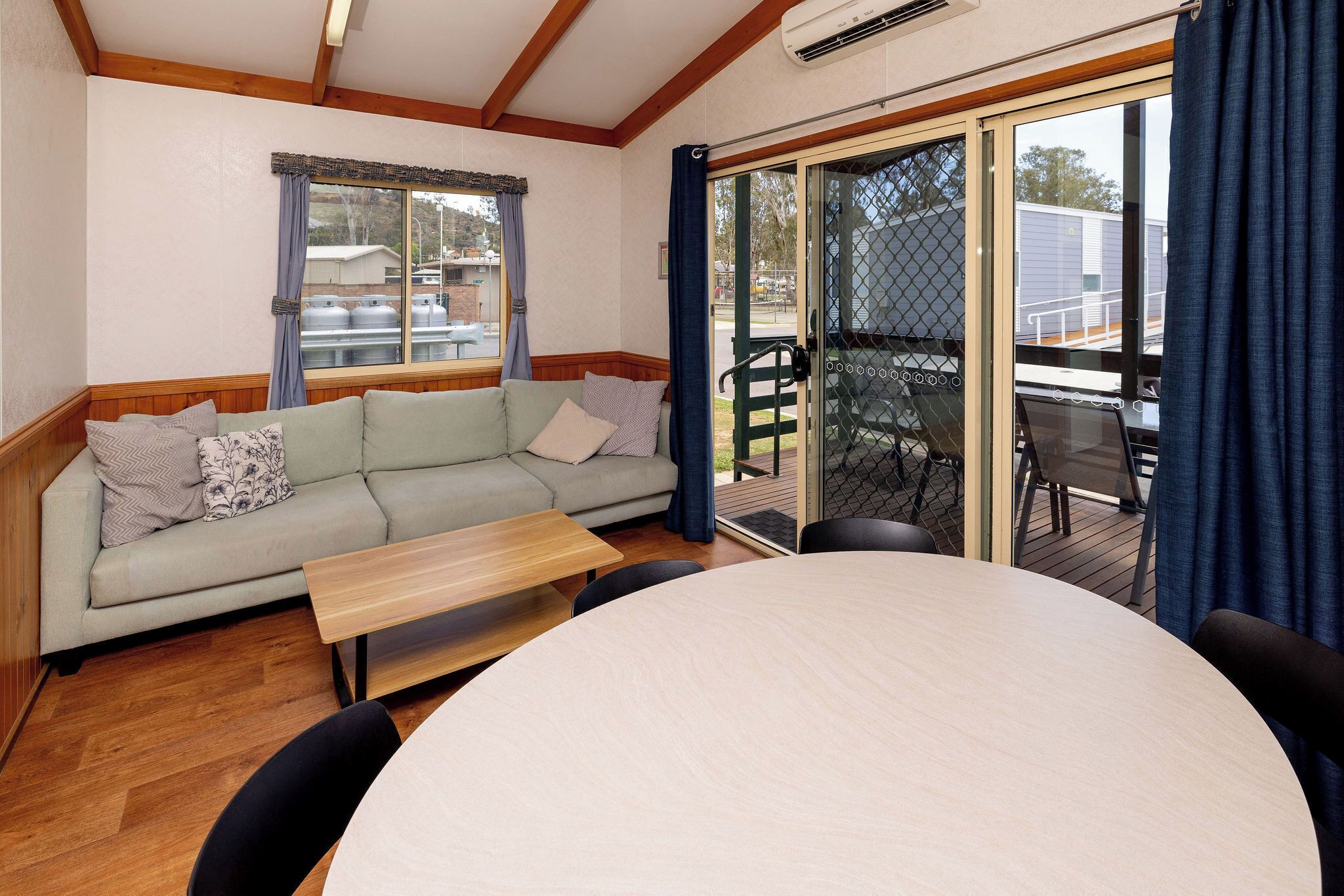 A cozy room with a sofa, a round table, and a sliding glass door leading to an outdoor deck.