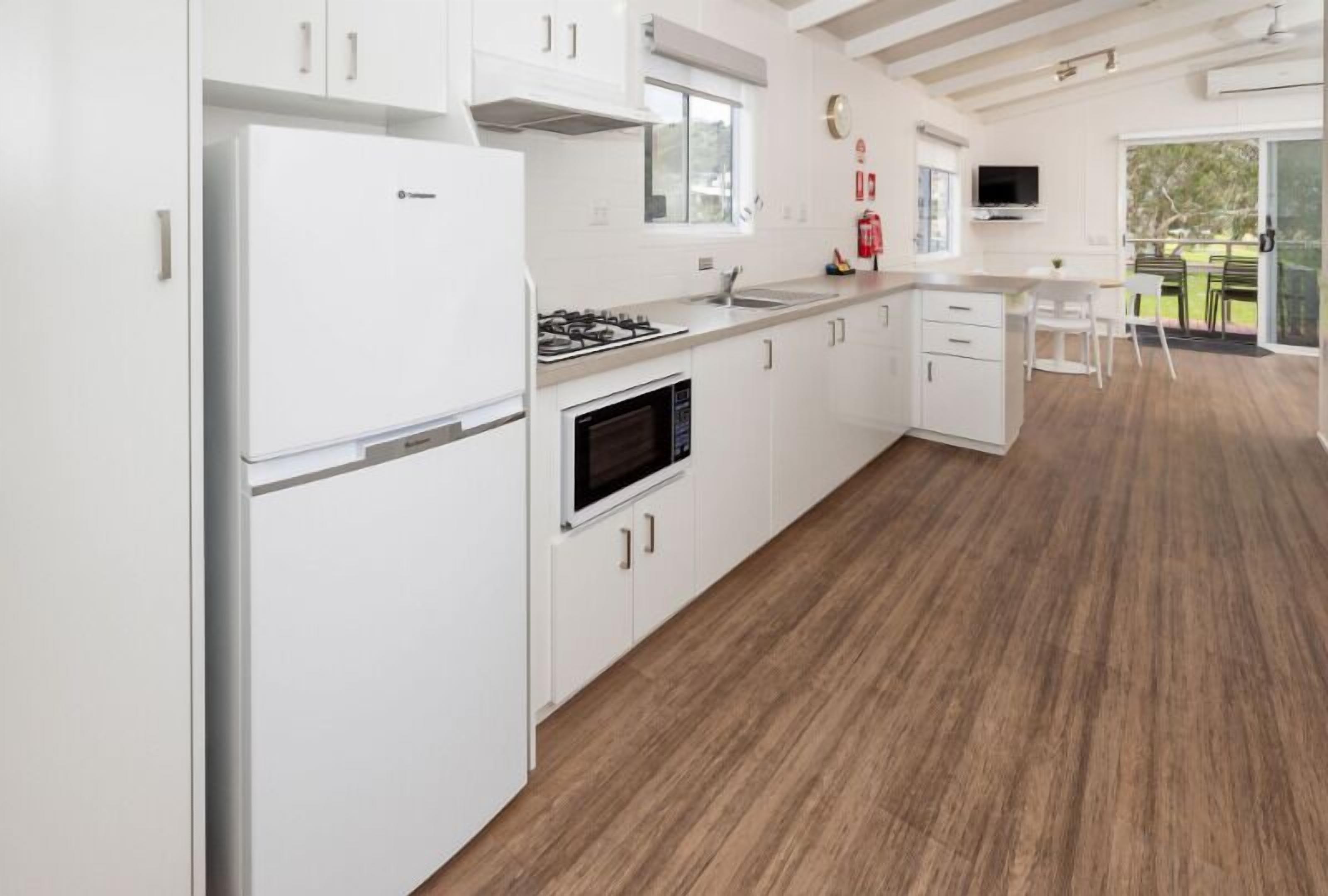 A modern kitchen with white cabinetry, a built-in oven, and a stove.