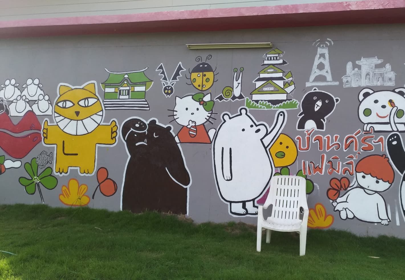 A wall with various cartoon characters and Thai text.