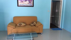 A living room with a sofa, a glass coffee table, and a framed picture on the wall. - Baansri Family (Kabin Buri)