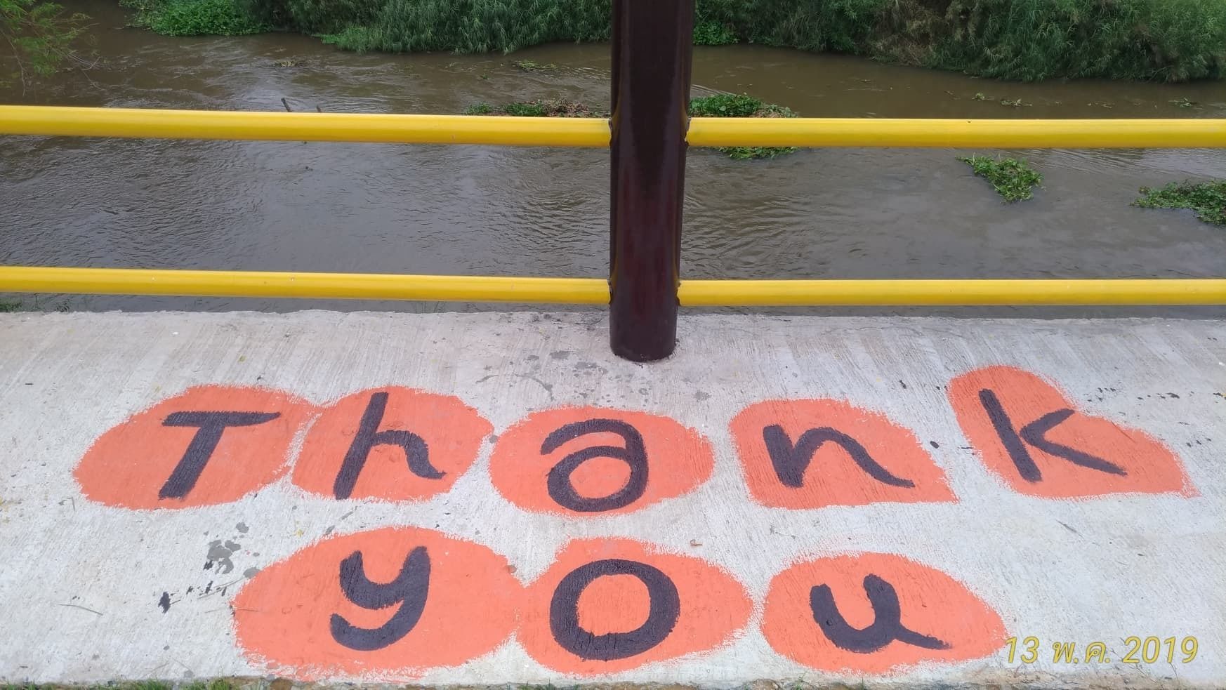 A concrete walkway with "Thank you" painted in orange and black.