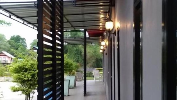 A covered outdoor corridor with a red roof, black metal slats, and wall-mounted lights. - Baansri Family (Kabin Buri)