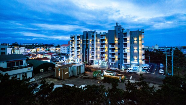A multi-story building with a modern architectural design, featuring balconies and illuminated windows. - Jeju Moseulpo Hotel (Seogwipo)