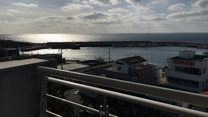 A coastal view with a marina, buildings, and a clear sky. - Jeju Moseulpo Hotel (Seogwipo)