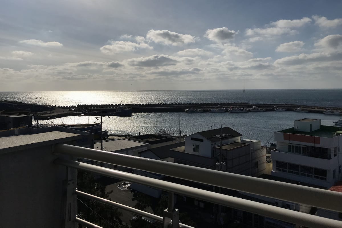 Blick auf die Küste mit einem Yachthafen, Gebäuden und einem klaren Himmel.