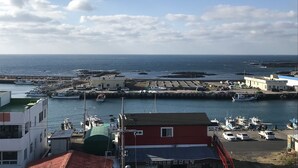 A coastal town with a marina, boats, and buildings along the waterfront. - Jeju Moseulpo Hotel (Seogwipo)
