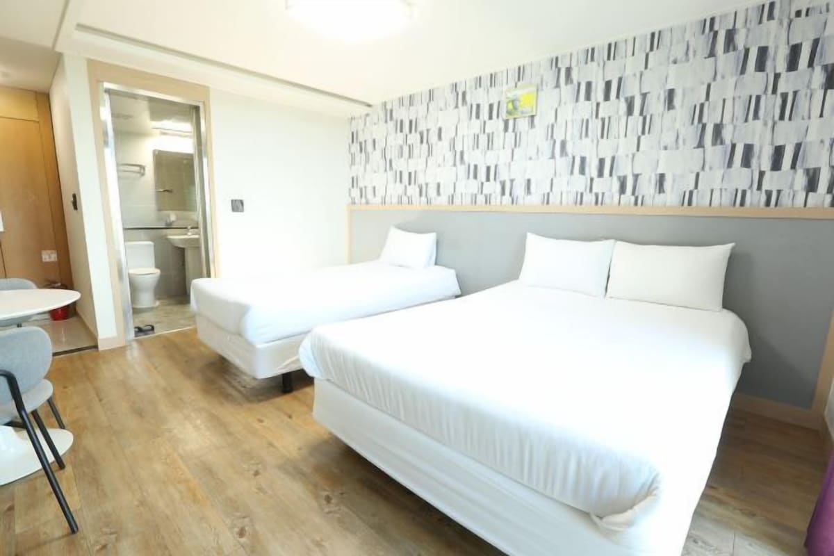 Une chambre d’hôtel avec deux lits simples, une petite table et une chaise.