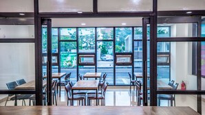 A restaurant with a modern interior, large windows, and a view of the street outside. - Jeju Moseulpo Hotel (Seogwipo)