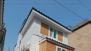 Un bâtiment à deux étages, doté d’une façade blanche et d’une partie en bois à l’étage supérieur.