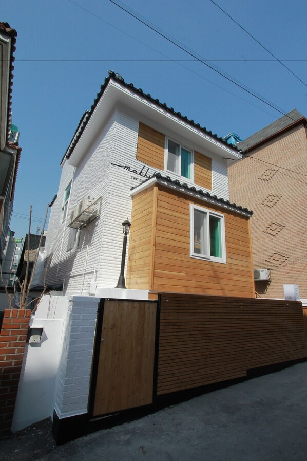 A two-story building with a white facade and a wooden section on the upper floor.