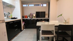 Une cuisine compacte dotée d’appareils électroménagers modernes, un coin repas avec des chaises et un téléviseur posé sur le comptoir.