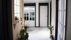 Un couloir avec des portes blanches, des plantes en pot et un mur en bois.
