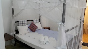 A bed with a canopy, pillows, a small bedside table, and a nightstand.