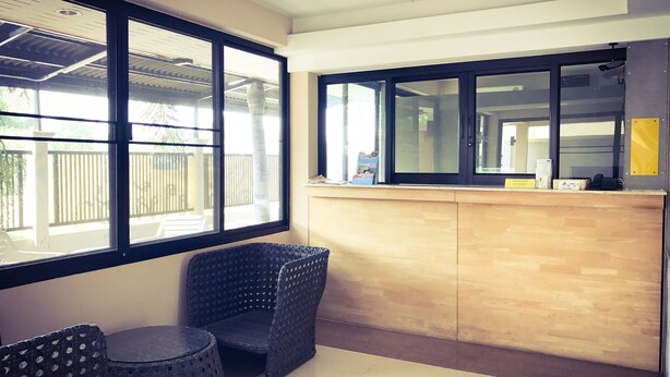 A reception area with a wooden counter, two patterned chairs, and a large window. - Sea Land View (Si Racha)