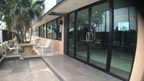 A covered outdoor area with a pool, lounge chairs, and a palm tree. - Sea Land View (Si Racha)