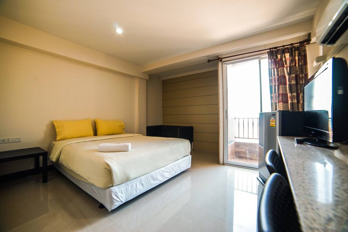 Une chambre d’hôtel avec un lit, un bureau, une chaise et une vue sur l’extérieur.