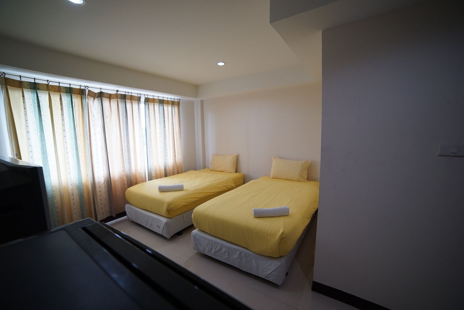 A hotel room with two beds, a TV, and a window with curtains.