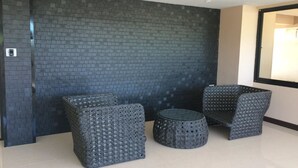 A modern interior with a dark brick wall, two square chairs, and a round ottoman. - Sea Land View (Si Racha)