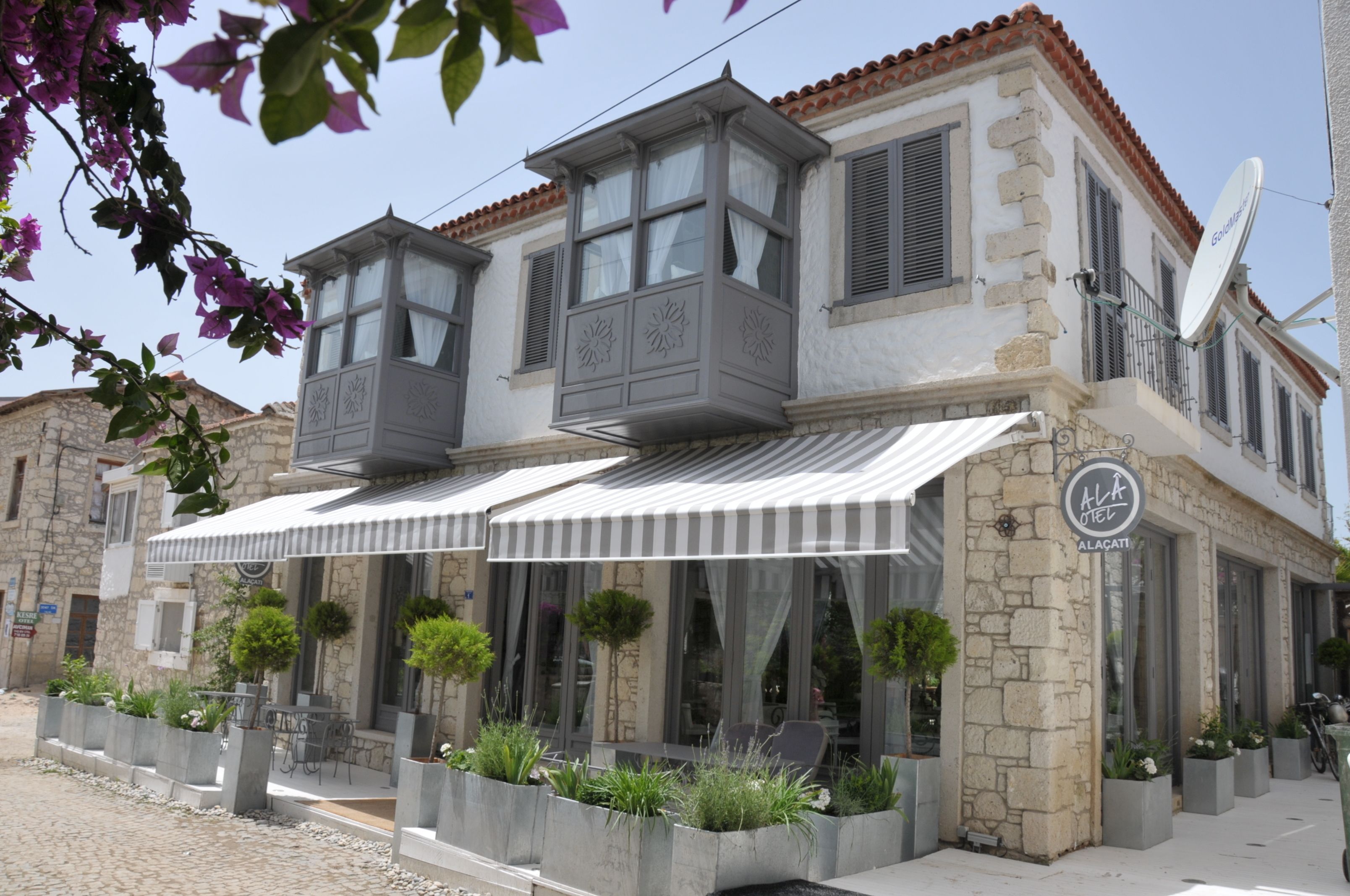 A two-story building with a balcony, outdoor seating, and a sign indicating it is a hotel.