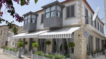 A two-story building with a balcony, outdoor seating, and a sign indicating it is a hotel.