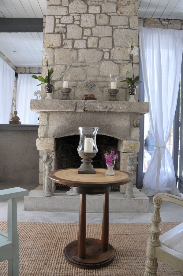 A stone fireplace with candles, a vase with flowers, and a table with a pitcher. - Ala Hotel - Special Class - Adults Only (Cesme)