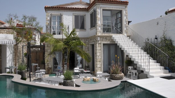 Una casa lujosa con piscina, mobiliario exterior y una escalera que conduce al piso superior.