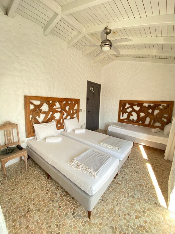 A room with two beds, a wooden headboard, a small wooden chair, a ceiling fan, and a stone-tiled floor. - Ala Hotel - Special Class - Adults Only (Cesme)