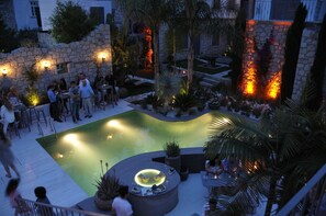 An outdoor pool area with stone walls, palm trees, and a hot tub. - Ala Hotel - Special Class - Adults Only (Cesme)