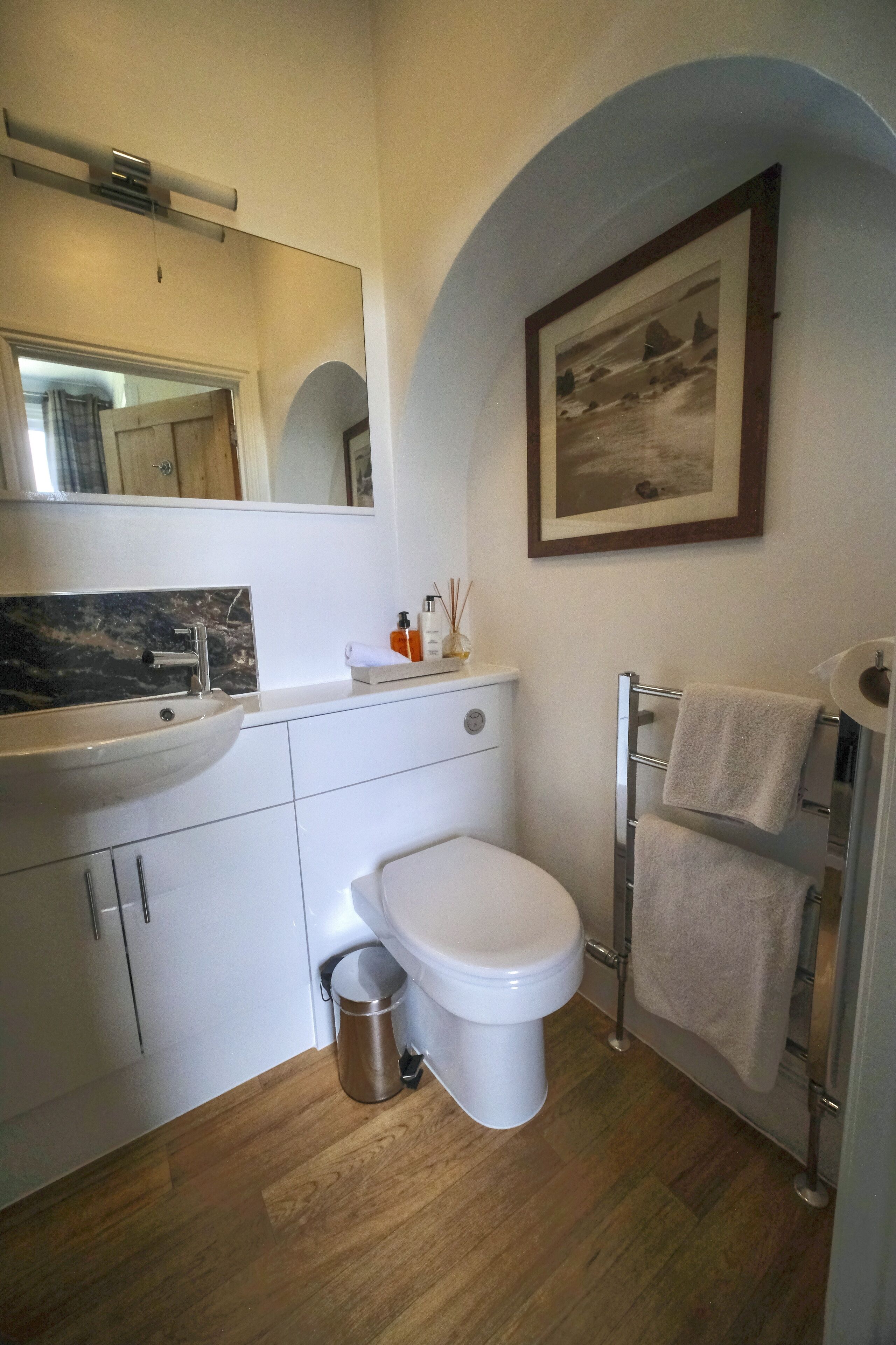 A modern bathroom with a white sink, a toilet, and a towel rack.