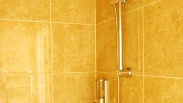 A bathroom with a shower system, including a handheld showerhead and a wall-mounted faucet.
