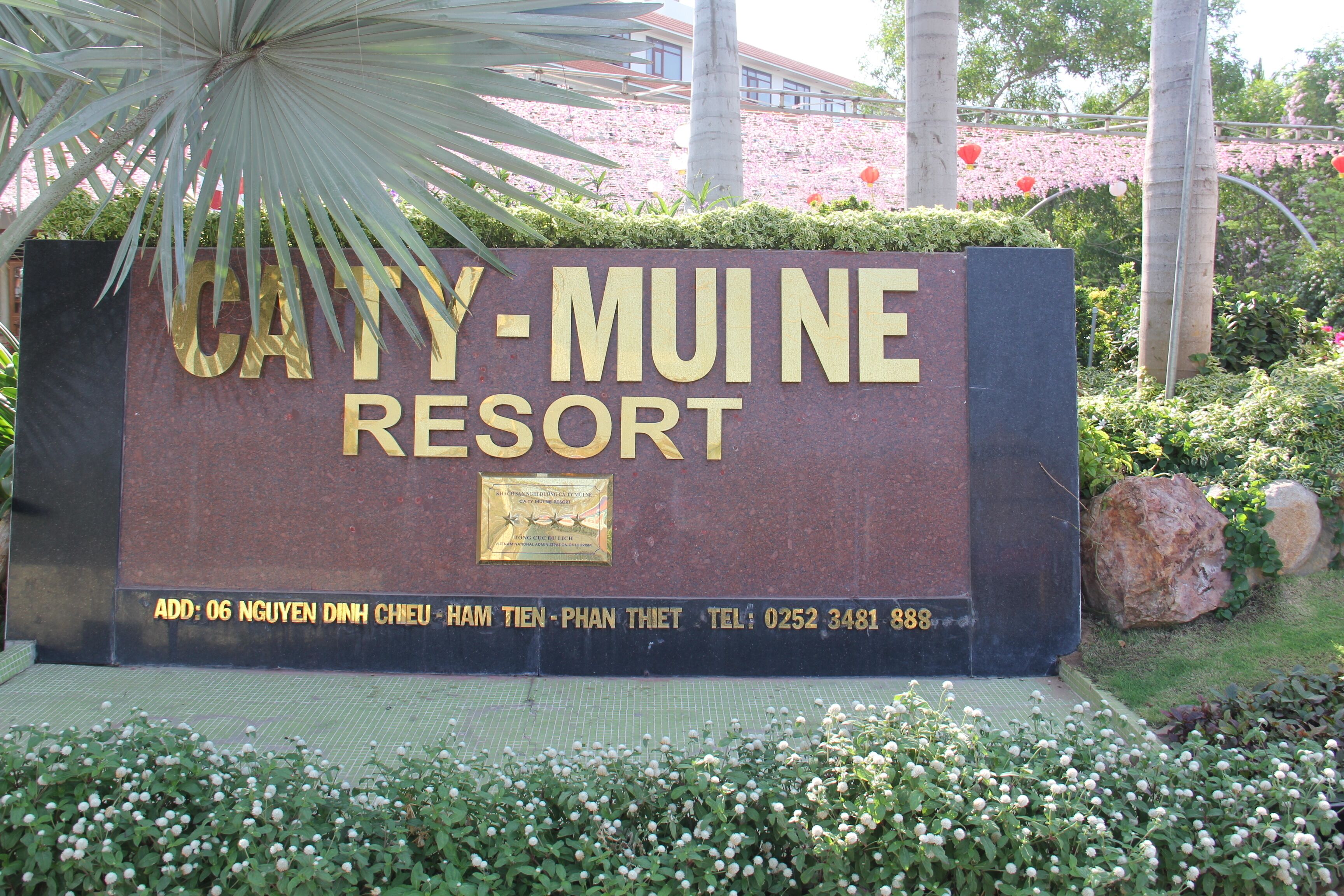 A sign for CATHY-MUI NE RESORT with contact information and address.