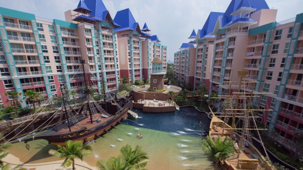 Ein Resort mit mehreren Gebäuden, einem Piratenschiff, einem Wasserpark und Palmen.