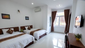 A hotel room with two beds, a TV, a desk, and a window with curtains. - The Times Hotel (Hue)