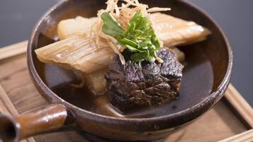 A bowl of beef with vegetables and noodles in a dark bowl.