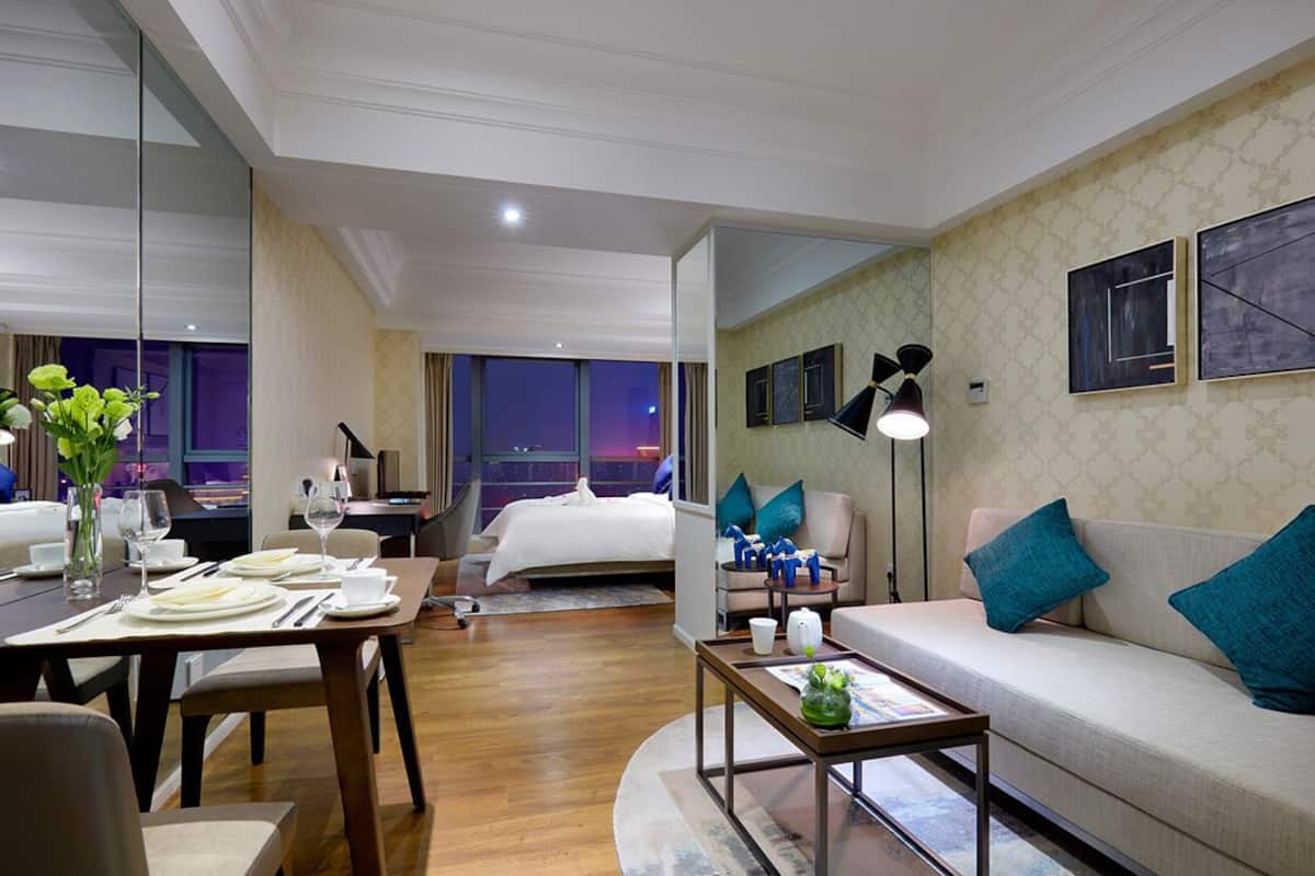 Ein Hotelzimmer mit Essbereich, einer Couch, einem Bett und einem großen Fenster.