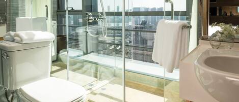 A modern bathroom with a glass-enclosed shower, a toilet, and a sink.