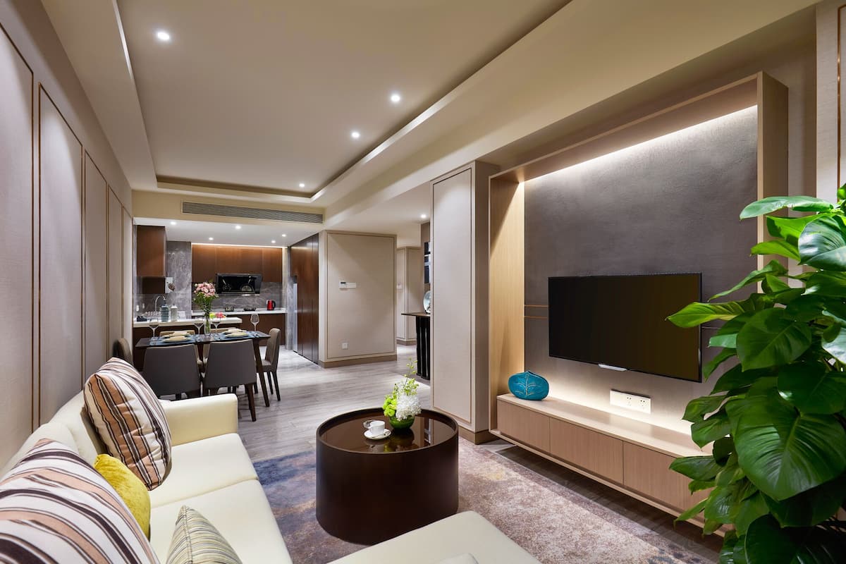 Ein modernes Wohnzimmer mit einer Couch, einem Couchtisch und einem flachbildfernseher an der Wand.