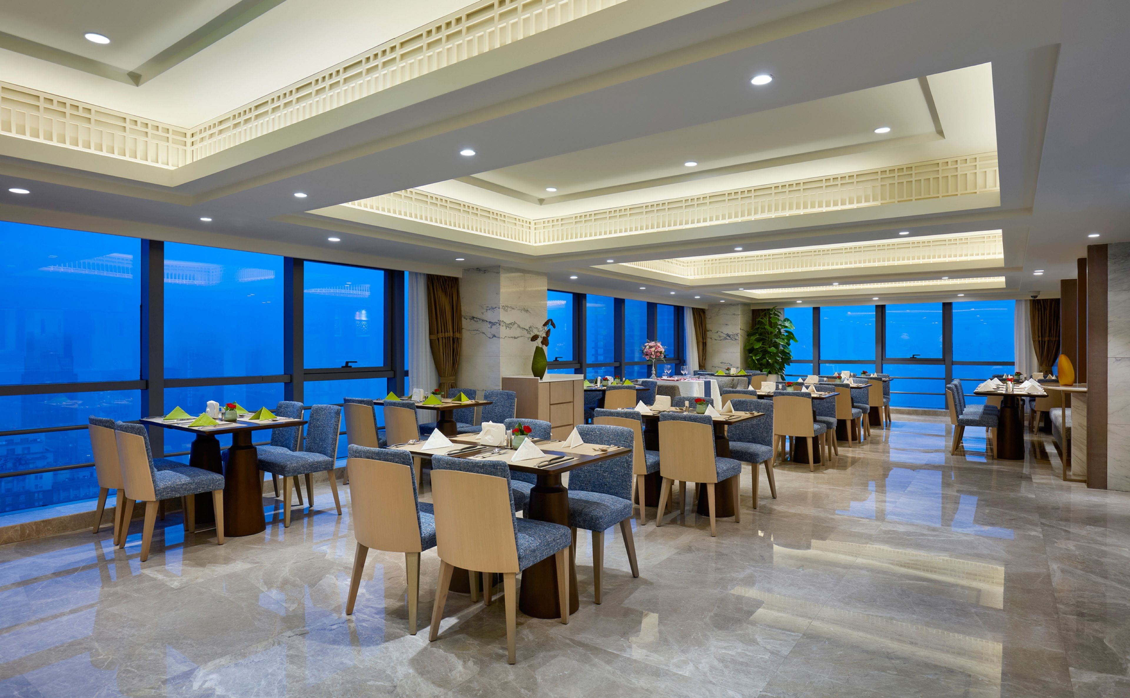Un comedor amplio con techos altos, ventanas grandes y muebles modernos.