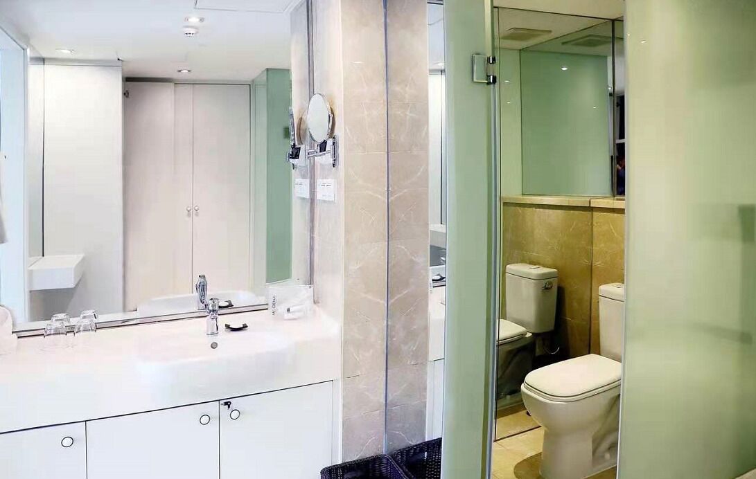 A modern bathroom with a large mirror, a white sink, and a toilet.